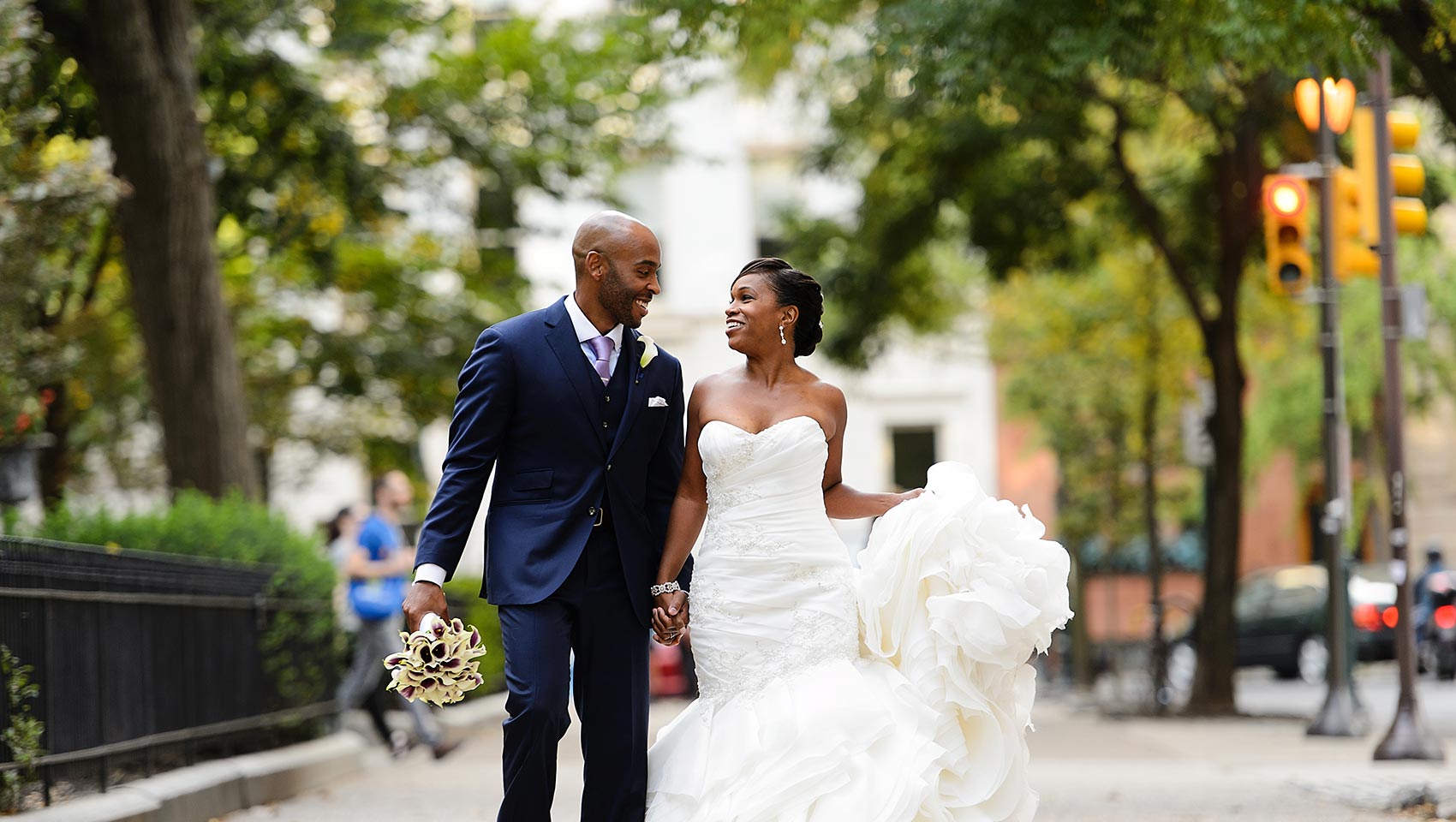 Bride and groom walk down the street, hand in hand, staring into each others eyes