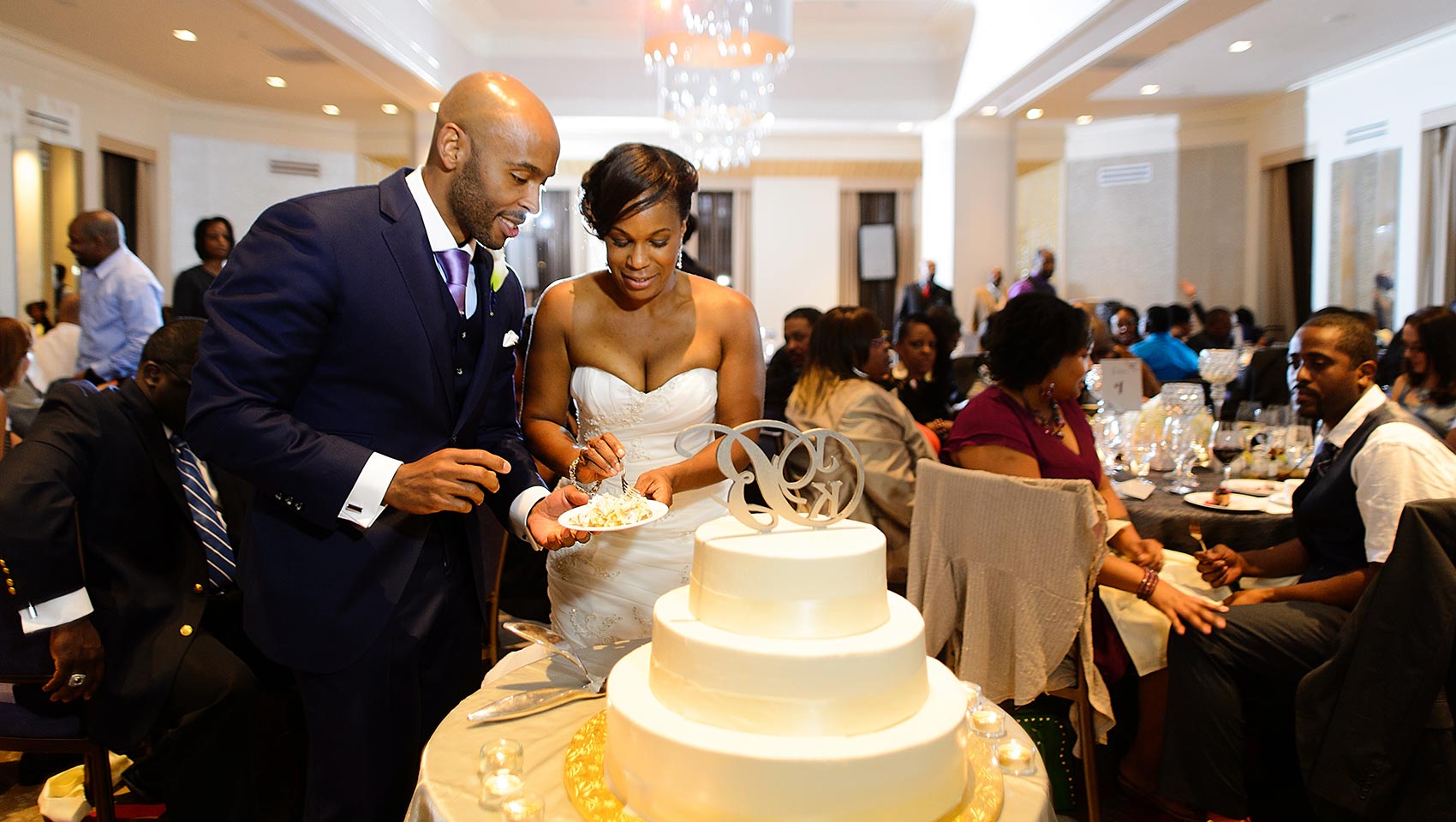 Bride and groom cut their wedding cake while others look on