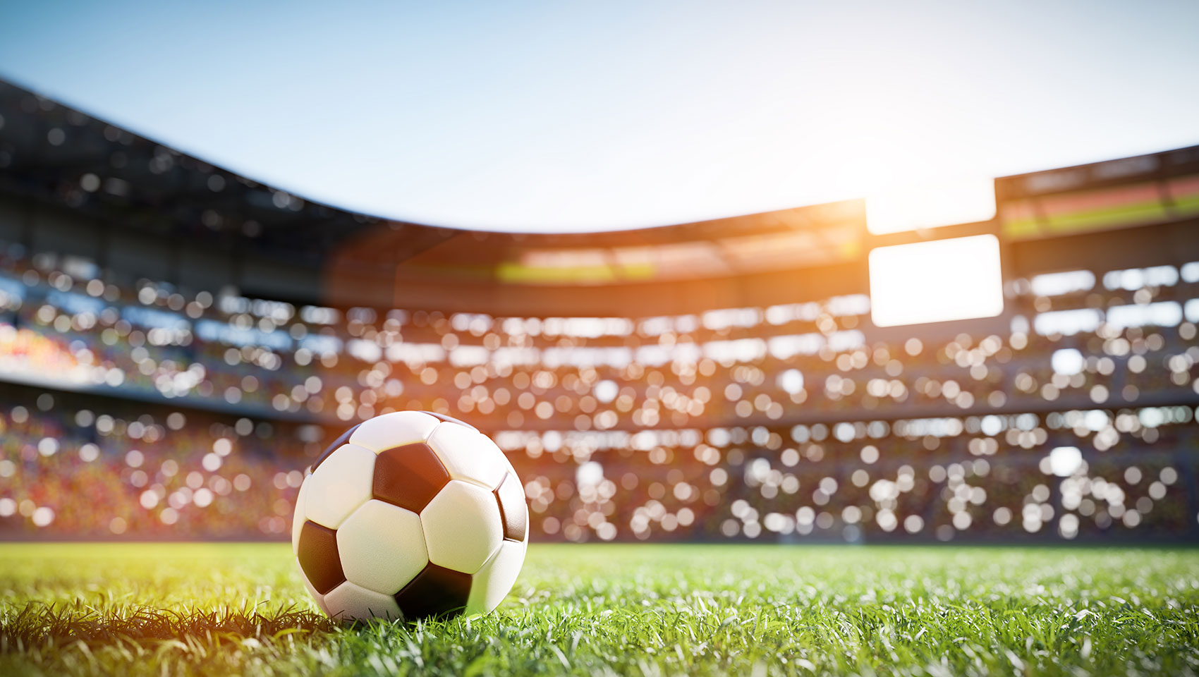 Soccer ball on pitch with stadium in background