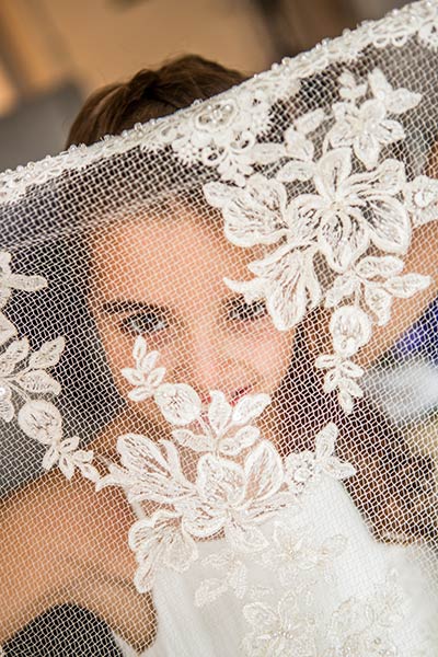 young girl holding Bride's veil in front of her face